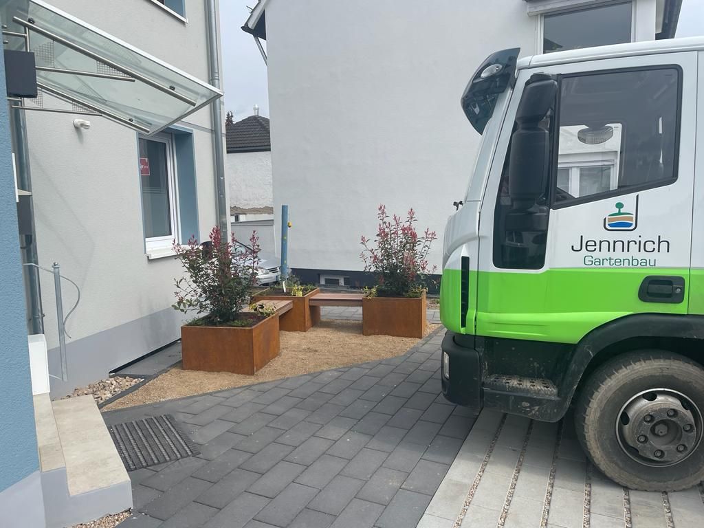 Unser Firmenwagen mit Jennrich-Logo vor einem fertigen Vorgarten