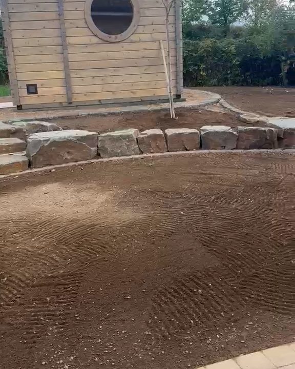 Vorher: gefräste und planierte Fläche mit Mutterboden vor Gartenhaus und Steinstufen